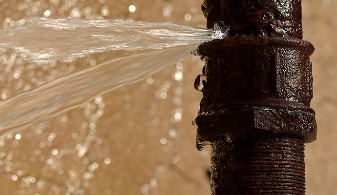 Broken, rusty water pipe spraying water.